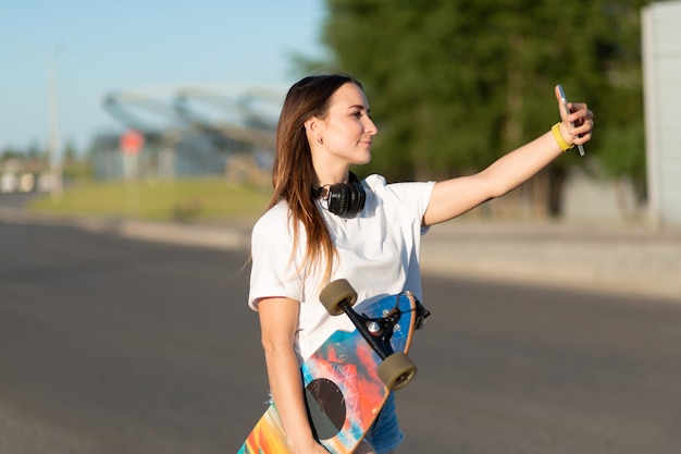 Fille faire selfie avec longboard sur téléphone mobile