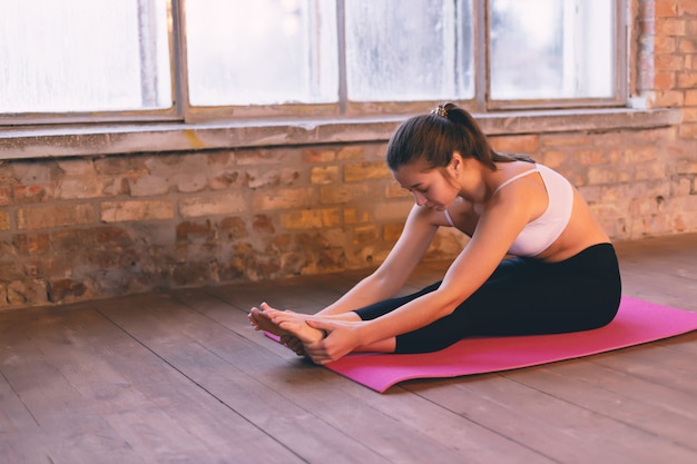 Photo fille faisant une asana se penchant en avant avec ses mains vers ses jambes