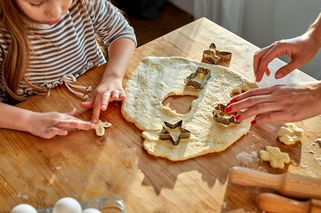 Fille faisant des biscuits avec la mère, aidez à étaler la pâte à l'aide de moules pour faire les boutures de biscuits