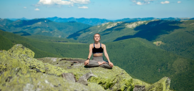 Fille faisant du yoga au sommet de la montagne.