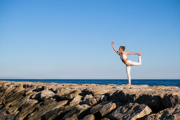 Photo fille faisant du yoga sur les rochers sur la plage