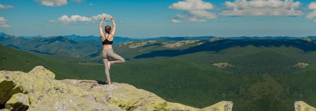 Fille faisant de l'exercice de yoga pose de lotus au sommet de la montagne