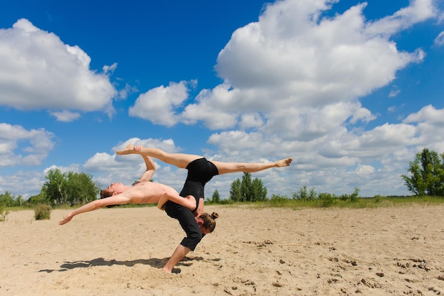 Fille faisant des fentes contre les nuages du ciel Un homme au torse nu sur le sable