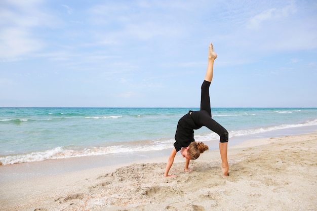 Fille faisant de la gymnastique sur la plage.