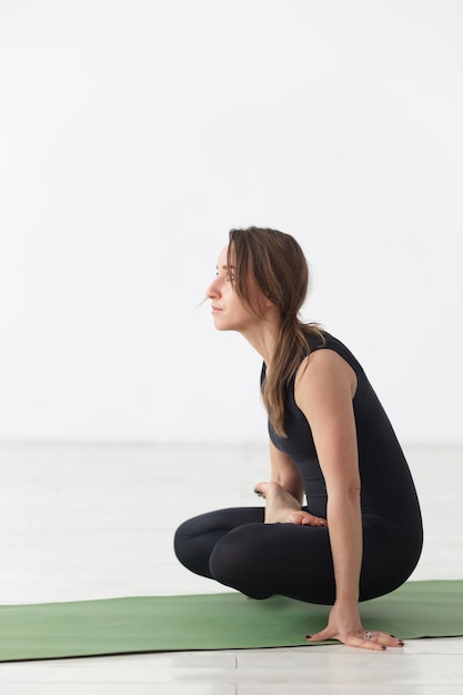 Une fille fait une asana difficile de la position du coq de yoga kukkutasana