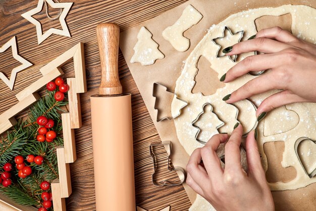 La fille fait des biscuits de Noël de pain d'épice utilisant la forme pour cuisiner