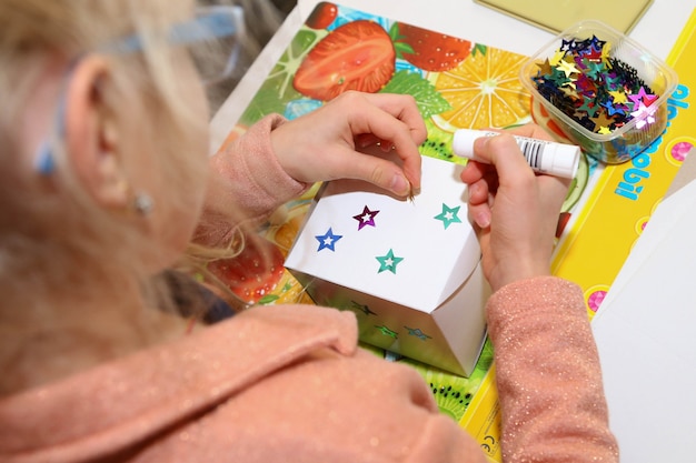 La fille fait une boîte-cadeau colle sur ses étoiles