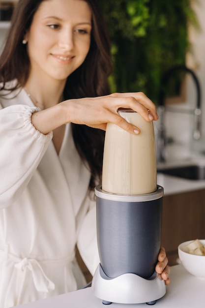 Une fille fait un cocktail dans un mixeur de fruits dans la cuisine Régime pour perdre du poids