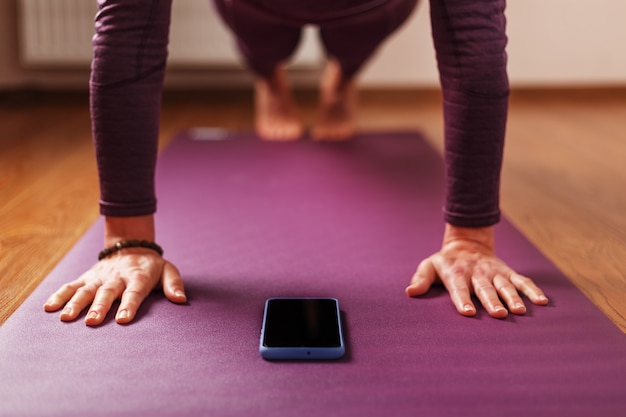 Une fille fait du yoga avec un smartphone