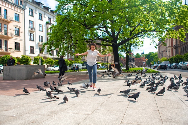 Une Fille Fait Peur à Un Troupeau De Pigeons Sur La Place De La Ville