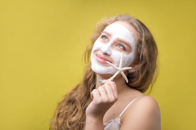 La fille fait des procédures avec un masque cosmétique sur son visage.
