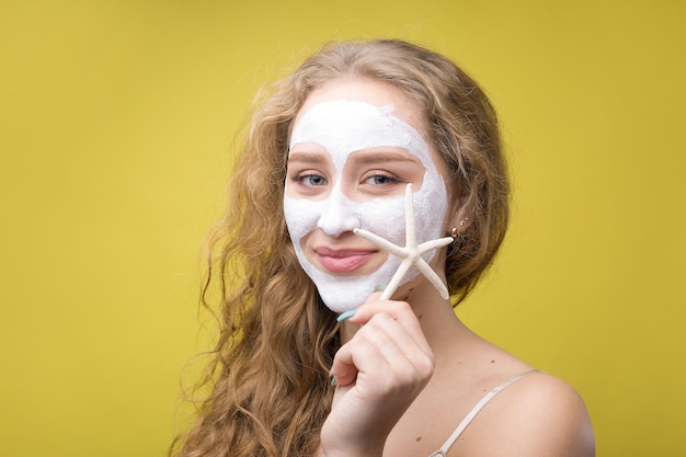 La fille fait des procédures avec un masque cosmétique sur son visage.