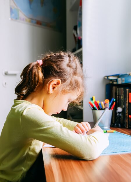 Une fille fait ses devoirs à la maison.