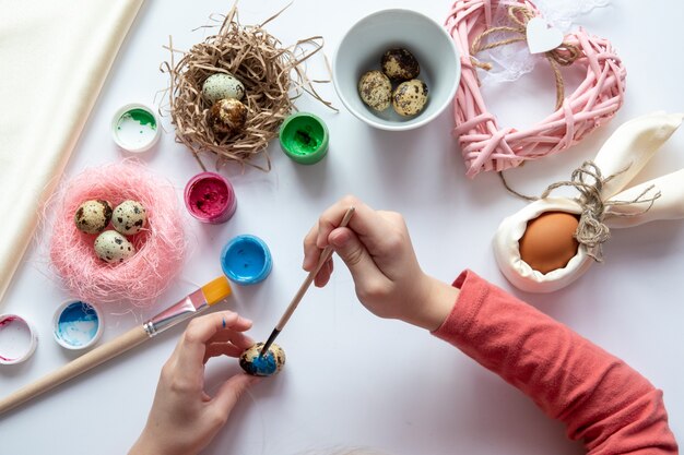 La fille fait de la vannerie de perles et d'oeufs pour Pâques