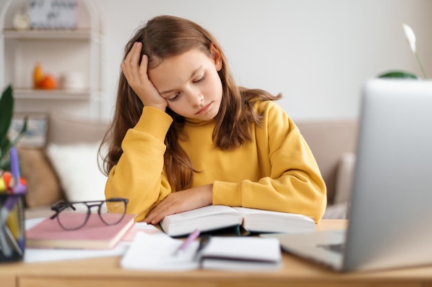 Fille fatiguée apprenant à la maison dans sa chambre