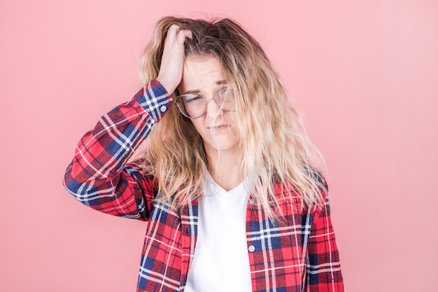 Fille fatiguée endormie avec des cheveux ébouriffés sur rose