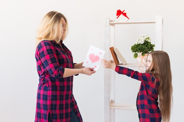 Fille félicite maman et lui donne une carte postale