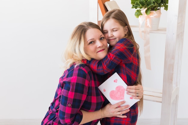 Fille félicite maman et lui donne une carte postale