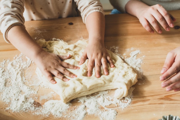 Fille et femme cuisinent à la maison dans une cuisine un enfant remue la farine pétrir la pâte sur la table à la main