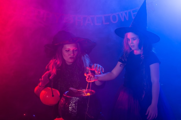 Fille et femme drôles d'enfant dans des costumes de sorcières pour Halloween avec Jack citrouille.