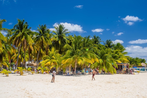 Fille femme et garçon jouent avec un ballon sur une plage de sable blanc avec cocotiers Isla Mujeres island Mer des Caraïbes Cancun Yucatan Mexique