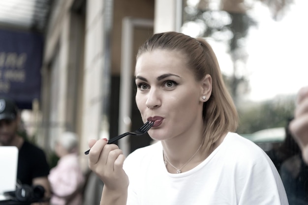 Photo fille ou femme mange avec une fourchette dans un café à paris, france. nourriture, collation, manger. faim, concept d'appétit.