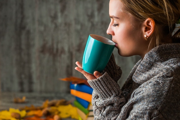 Fille femme en pull, boire une tasse de thé chaud, café. Automne froid, confortable. Tenant une tasse dans ses mains.