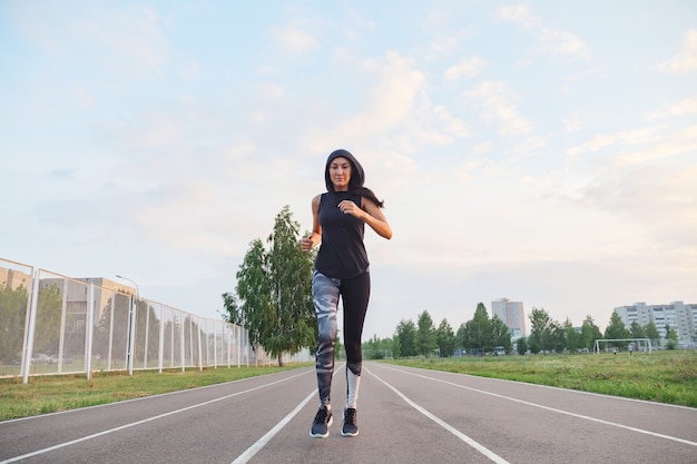 Fille de femme sportive qui court au stade en plein air.