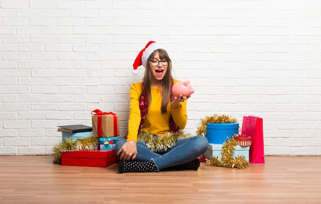 Fille fêtant les vacances de Noël surpris en tenant une grande tirelire