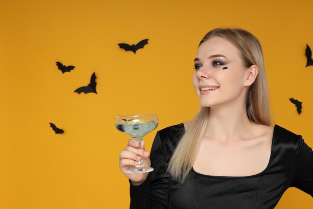 Une fille à une fête dans le style d'Halloween avec un cocktail dans les mains