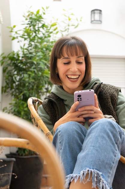 Fille fille très heureuse avec une position détendue assise sur la chaise en regardant le mobile avec un énorme