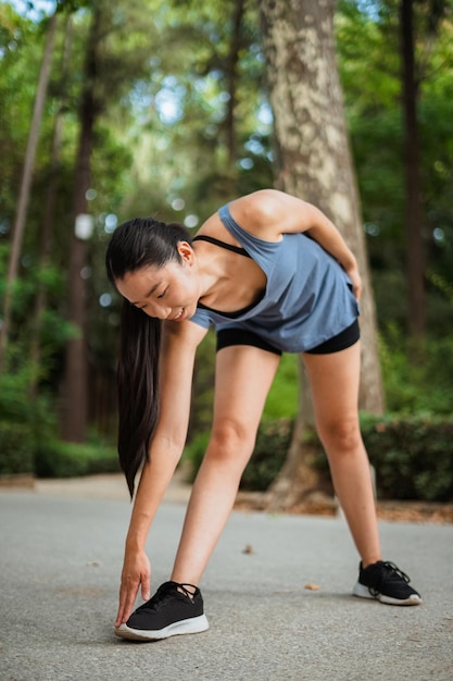 Fille de fitness asiatique s'échauffant dans le parc avant de faire du jogging