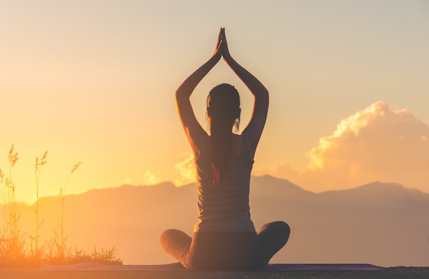 Fille de fitness silhouette pratiquer l&#39;yoga sur la montagne avec la lumière du soleil