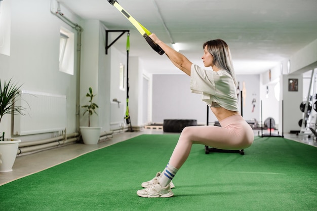 Fille de fitness sportive faisant des exercices avec des sangles TRX dans la salle de gym