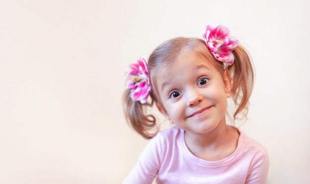 Une fille avec des fleurs dans les cheveux fait des grimaces à la caméra