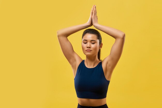 Fille flexible tenant les mains de prière au-dessus de la tête