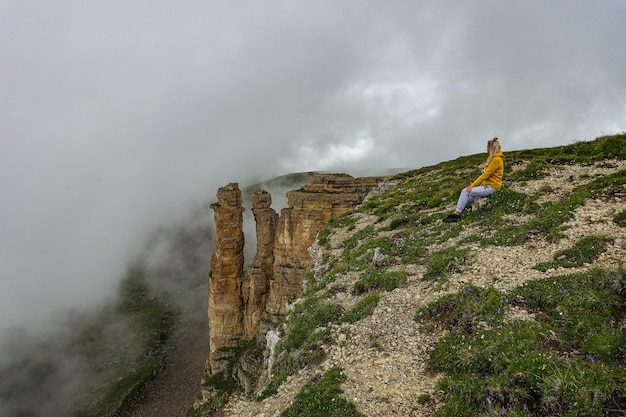 Une fille sur le fond de deux rochers de moines dans un nuage, plateau de Bermamyt, Russie.