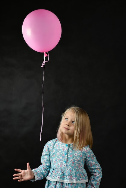 La fille sur fond noir souffle un ballon