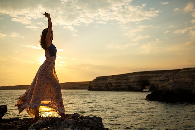 La fille sur le fond d&#39;un paysage marin et coucher de soleil magnifique, silhouette d&#39;une fille sur une falaise, sur une falaise, beau ciel et mer