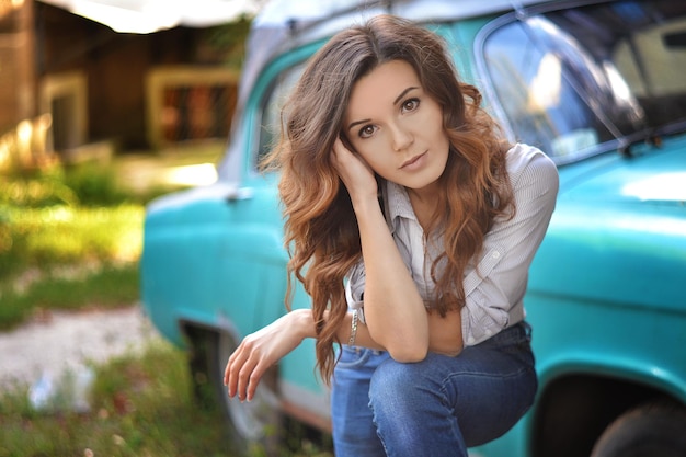 Photo fille sur le fond d'une vieille voiture