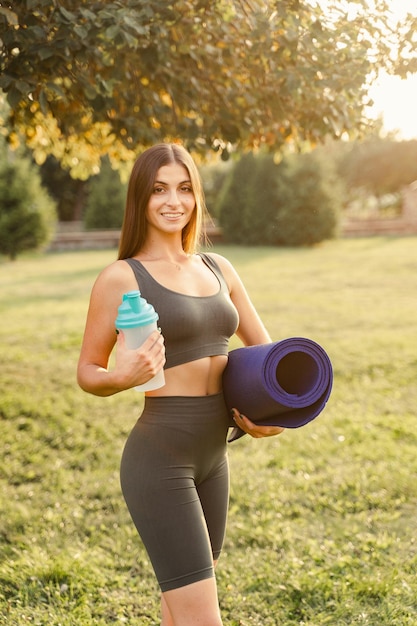 Fille en forme athlétique avec tapis d'entraînement et bouteille d'eau Publicité extérieure pour un magasin de nutrition et d'équipements sportifs