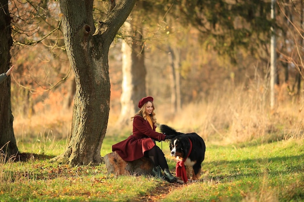 Une fille française est assise dans un parc d'automne avec son chien Gants et manteaux pour femmes