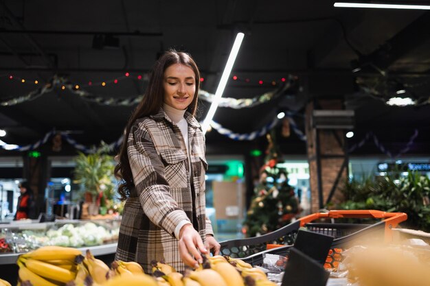 Fille gaie achetant des bananes à l'épicerie