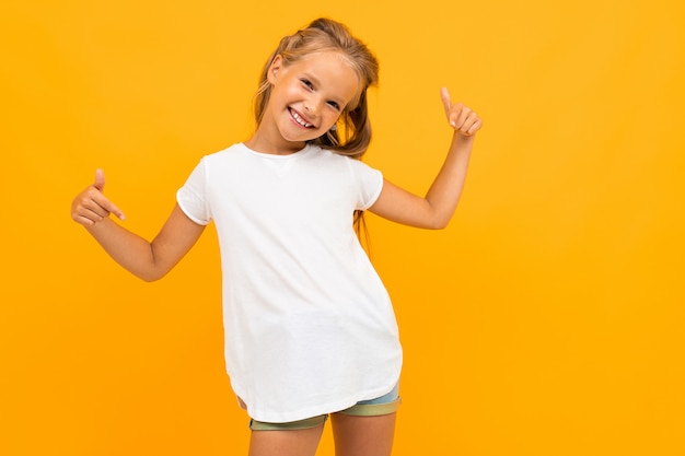 Fille Gaie Dans Un T-shirt Blanc Sourit Contre Un Jaune