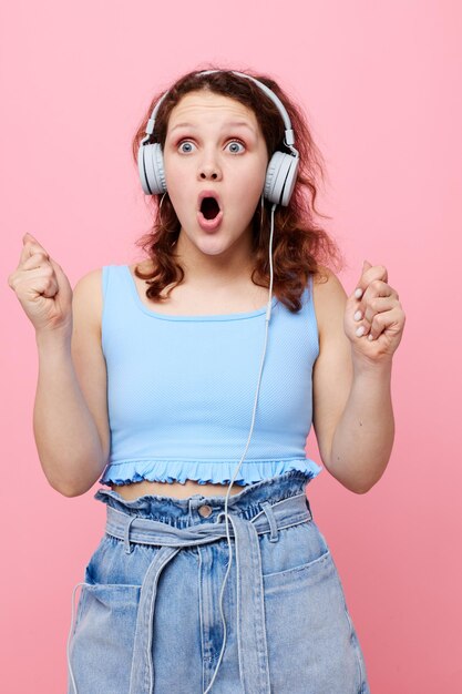 Fille gaie avec des écouteurs dansant la musique de divertissement fond rose inchangé