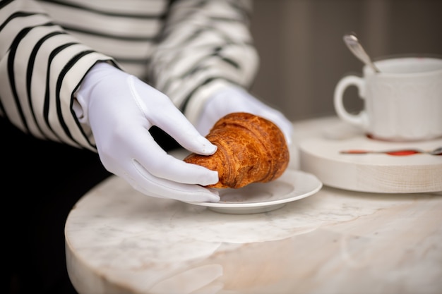 Fille en gants blancs tenant un gros plan croissant