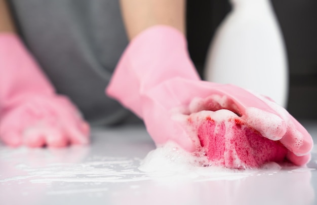 Une fille en gants de caoutchouc lave la table avec un détergent Concept de nettoyage de printemps Gros plan Mise au point sélective