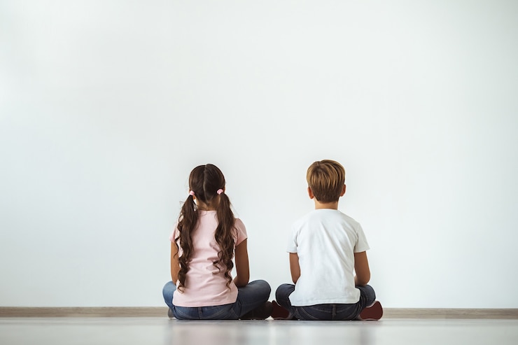 Photo la fille et un garçon assis sur le sol sur le fond du mur blanc