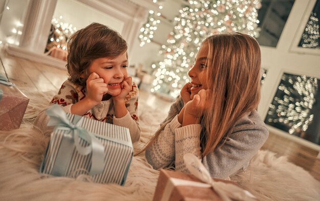 La fille et le garçon heureux avec des cadeaux posés sur le sol