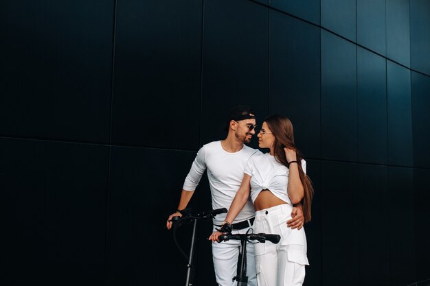 Une fille et un gars marchent sur des scooters électriques dans la ville, un couple amoureux sur des scooters.